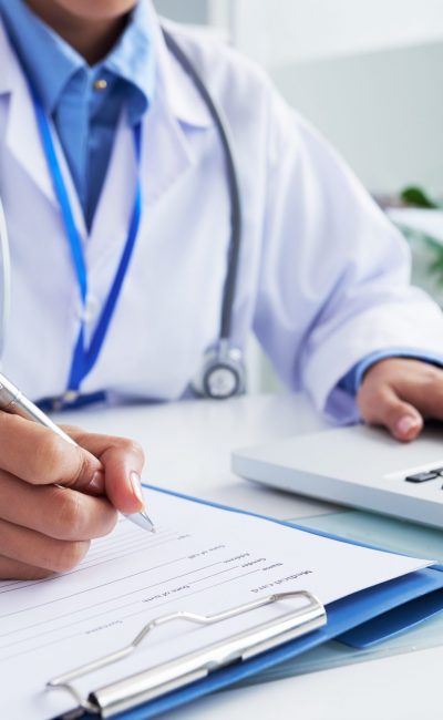 Doctor checking information in computer program before filling medical card